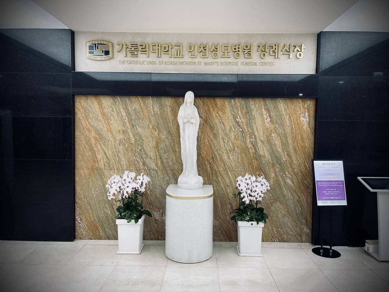 성모상과 금색 현판이 보이는 장례식장 로비