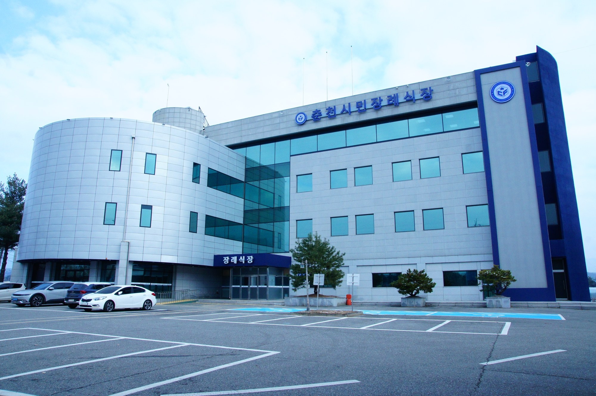 춘천시민장례식장 건물과 주차장이 보이는 정면 사진.